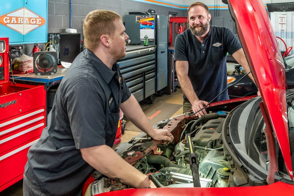 Two men are working on a red car in a garage. | The Garage in Renton