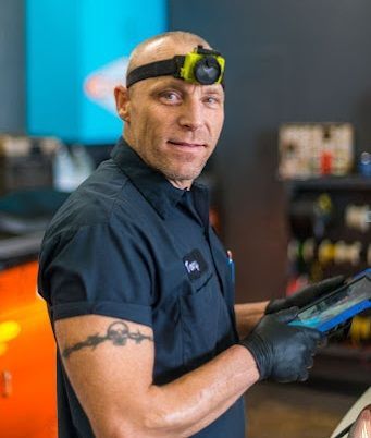 A man wearing a headlamp is holding a tablet in a garage. | The Garage in Renton