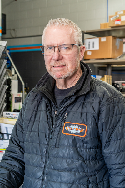 A man wearing glasses and a black jacket is standing in a warehouse. | The Garage in Renton