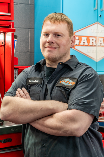 A man with his arms crossed in front of a garage sign | The Garage in Renton