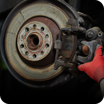 A person wearing a red glove is holding a brake caliper | The Garage in Renton