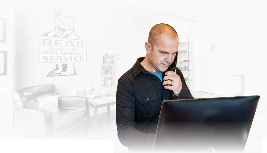 A man is talking on a cell phone while sitting in front of a laptop computer. | The Garage in Renton