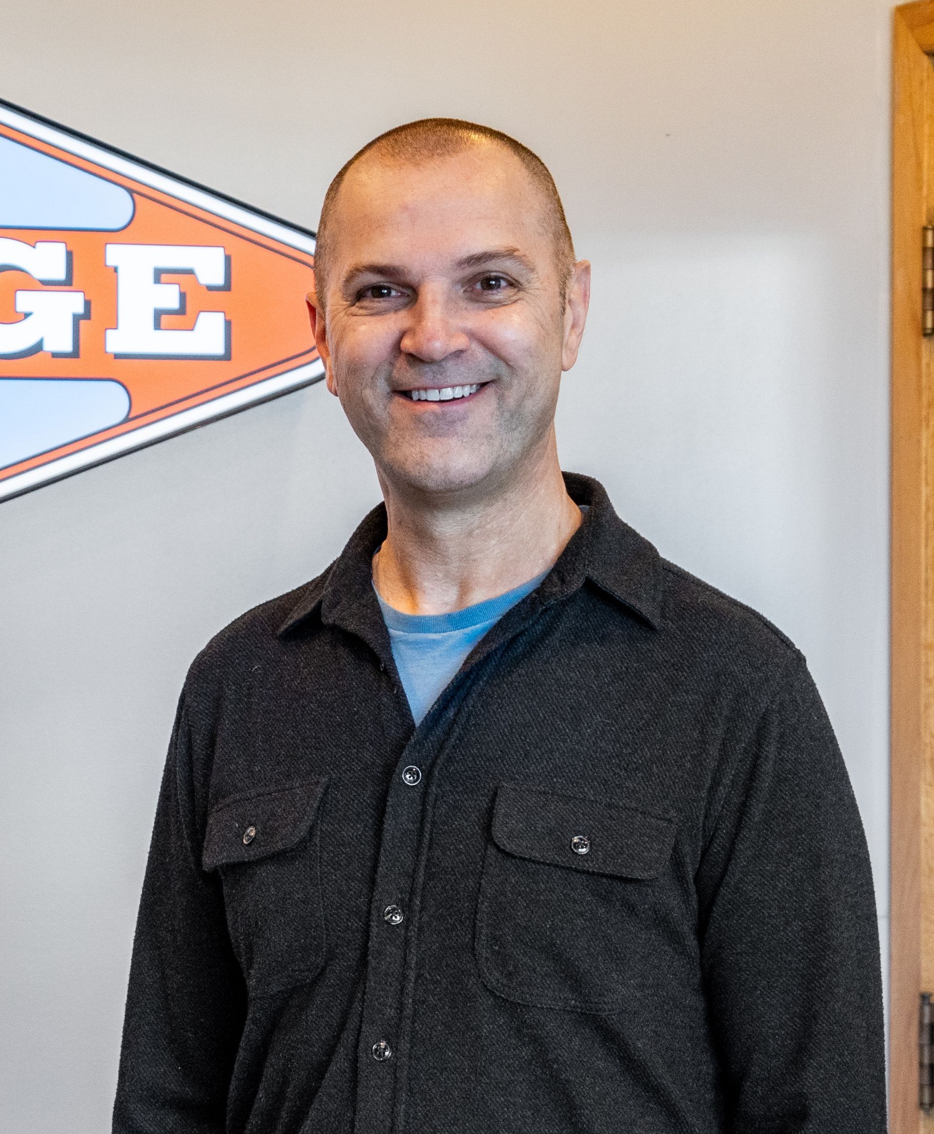 A man is smiling in front of a sign that says ge | The Garage in Renton