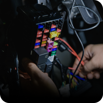 A person is working on a fuse box in a car | The Garage in Renton