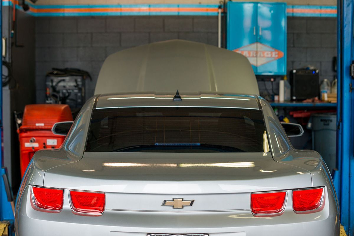 A silver chevrolet camaro is parked in a garage with the hood up. | The Garage in Renton
