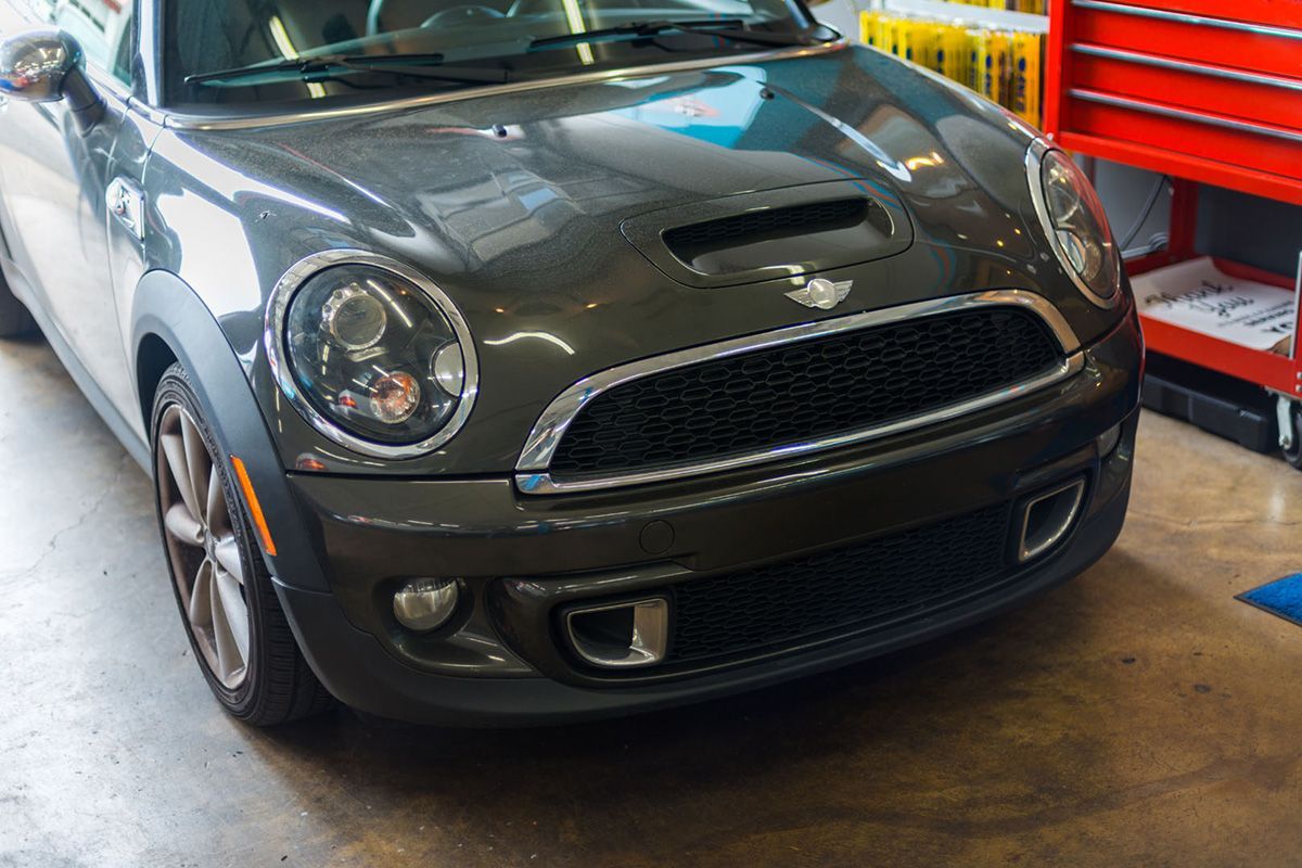 A gray mini cooper is parked in a garage next to a red toolbox. | The Garage in Renton