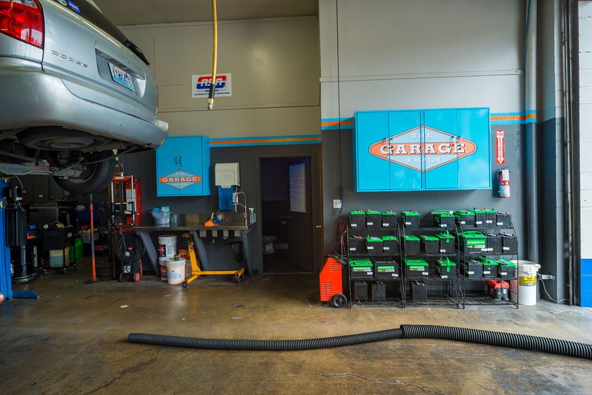 A car is parked in a garage next to a stack of batteries. | The Garage in Renton