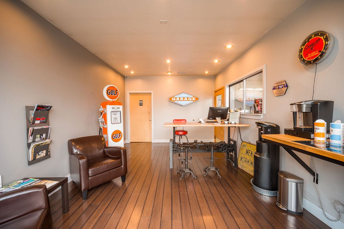 A waiting room with a chair , desk , and coffee maker. | The Garage in Renton