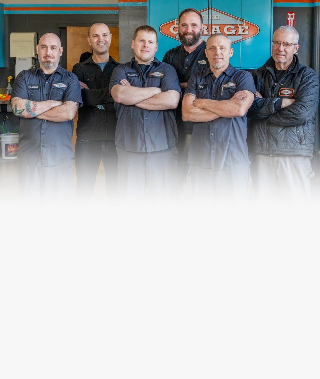 A group of men are posing for a picture in front of a garage sign. | The Garage in Renton