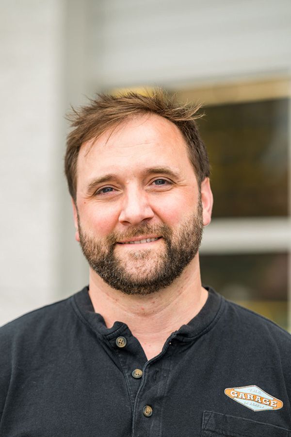 A man with a beard is wearing a black shirt and smiling for the camera. | The Garage in Renton