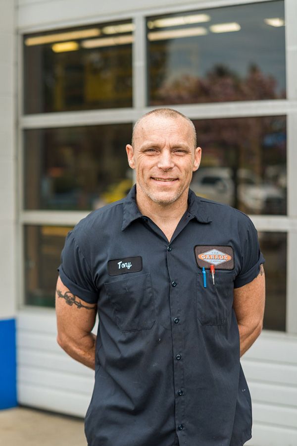 A man in a blue shirt is standing in front of a garage door. The Garage in Renton