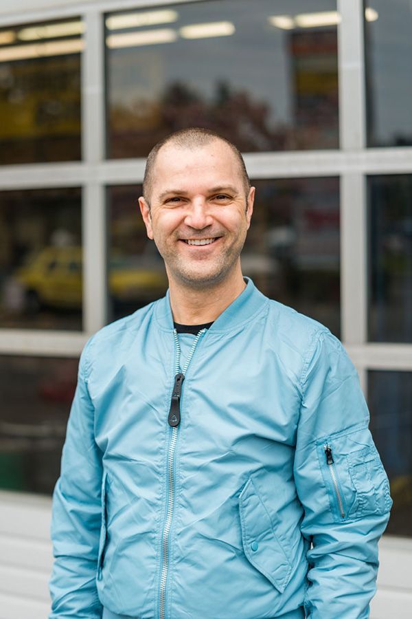 A man in a blue jacket is standing in front of a building. | The Garage in Renton
