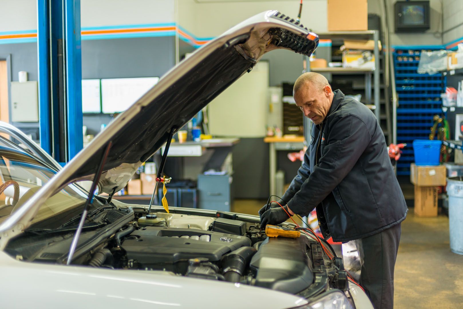A man is working on the engine of a car in a garage. | The Garage in Renton