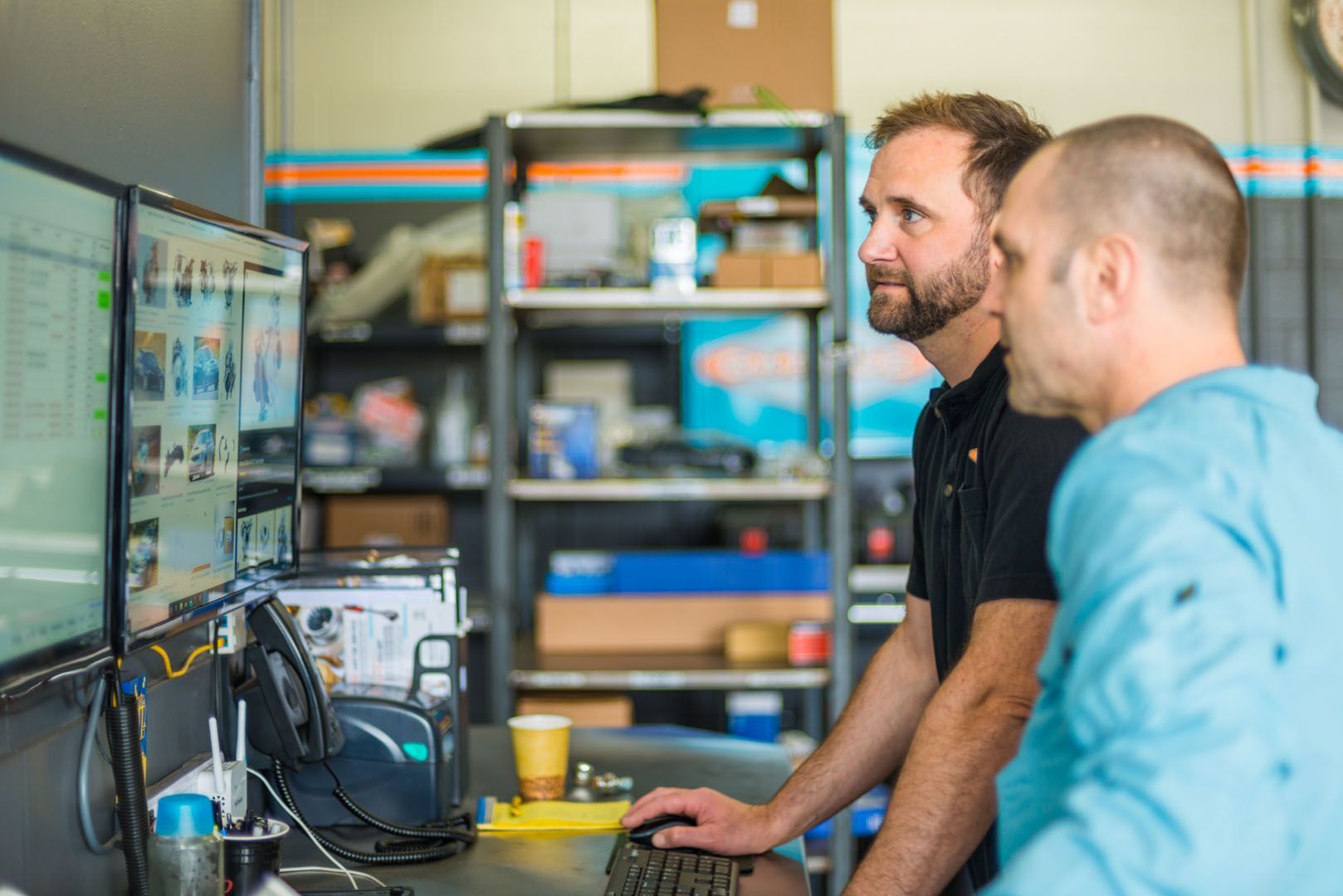 Two men are looking at a computer screen in a garage. | The Garage in Renton