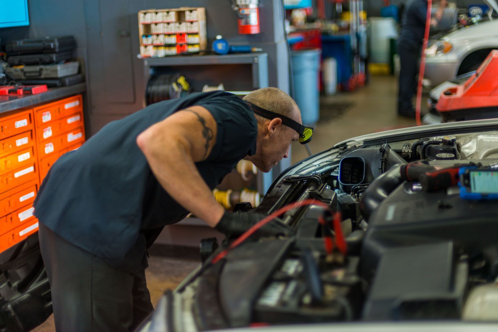A man is working on the engine of a car in a garage. | The Garage in Renton