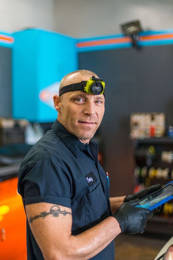 A man wearing a headlight and gloves is holding a tablet in a garage. | The Garage in Renton