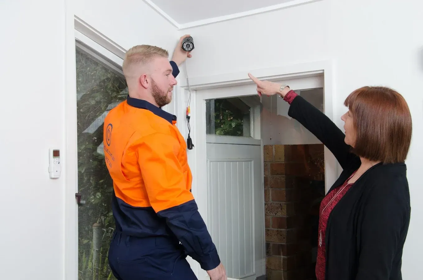 A Aurablue worker is helping client with light on wall — Aurablue Electric in Fullerton Cove, NSW