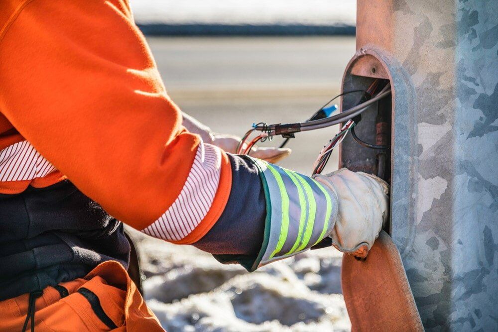 A Man in an Orange Jumpsuit is Working on a Pipe — Aurablue Electric in Fullerton Cove, NSW
