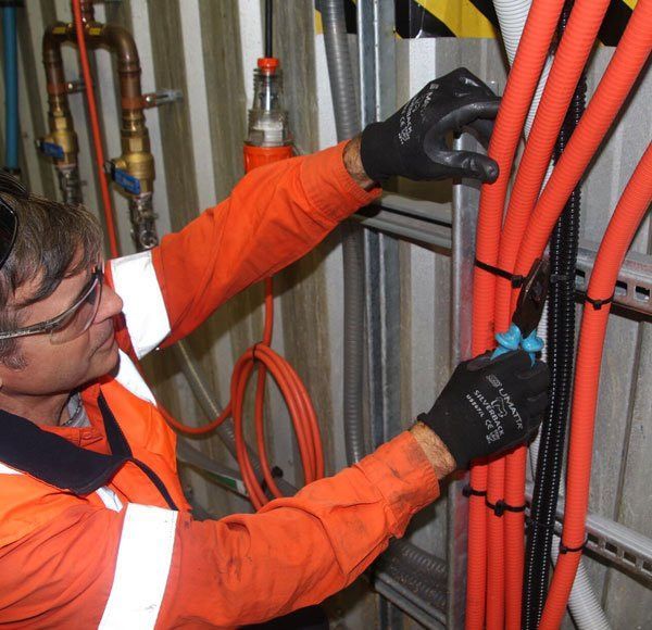 A Man Wearing Safety Gloves is Working on Electrical Wires — Aurablue Electric in Fullerton Cove, NSW
