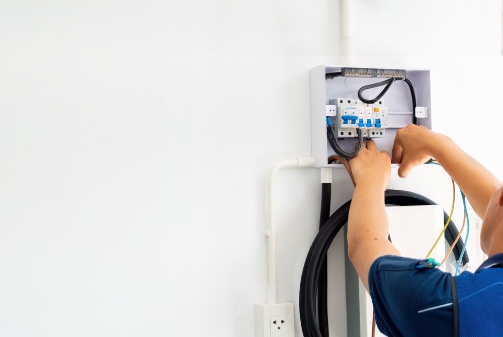 An Electrician is Working on an Electrical Box on a Wall — Aurablue Electric in Fullerton Cove, NSW