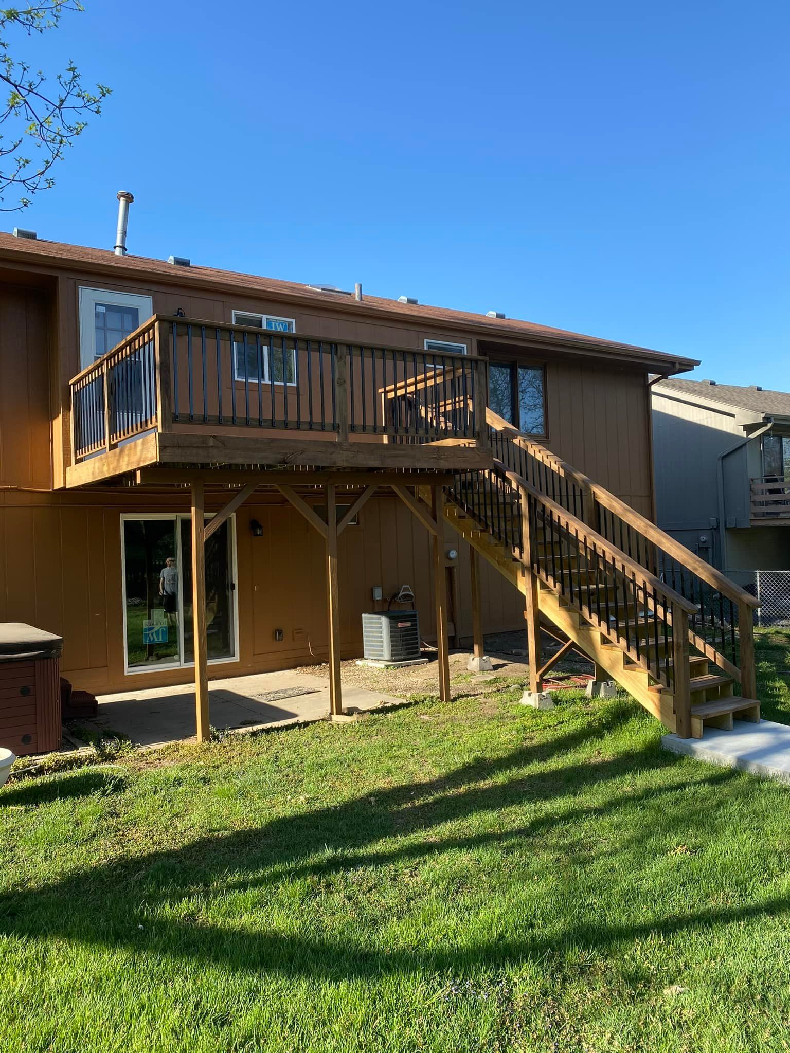 A house with a wooden deck and stairs in the backyard.