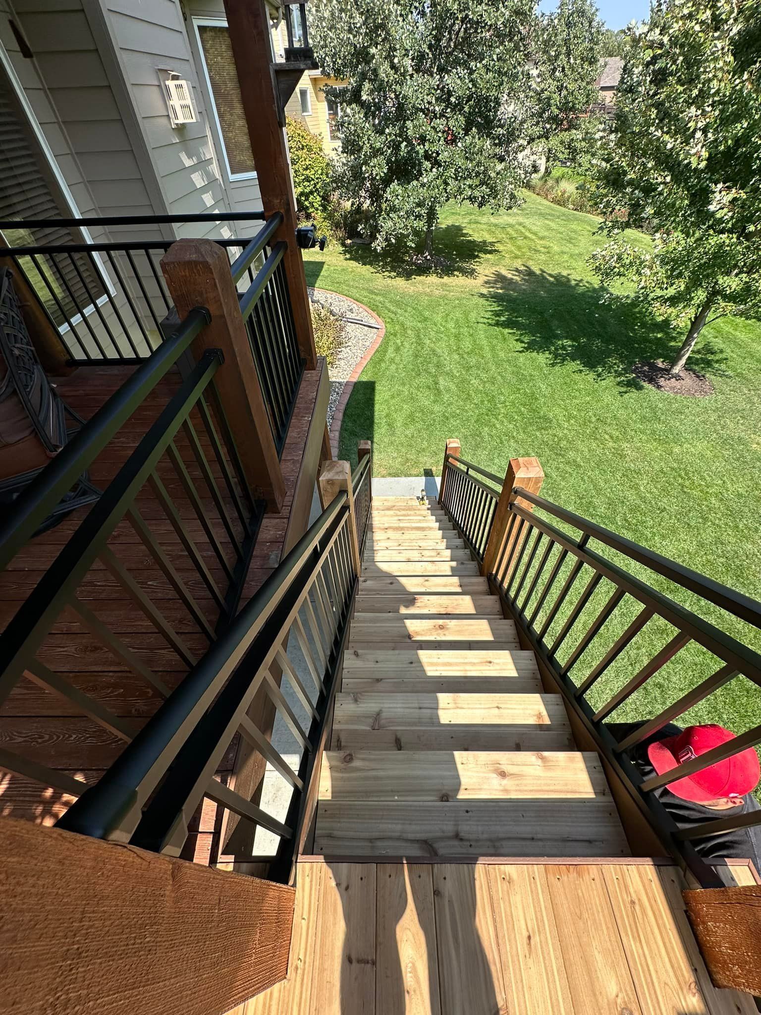 A wooden staircase leading up to a house with a metal railing.