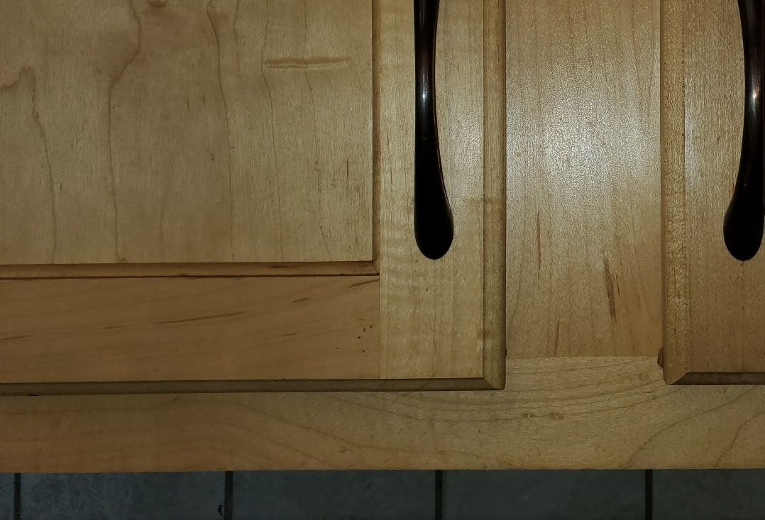 Light wood kitchen cabinet with dark drips on it.