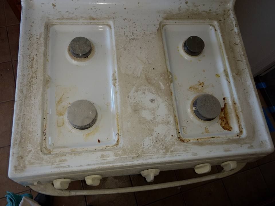 Dirty white stovetop with four burners, covered in food residue.