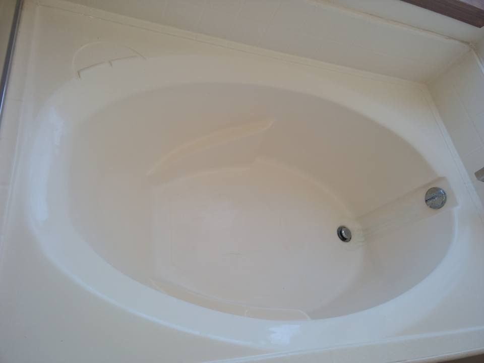 An oval, beige bathtub in a bathroom, with a drain visible.
