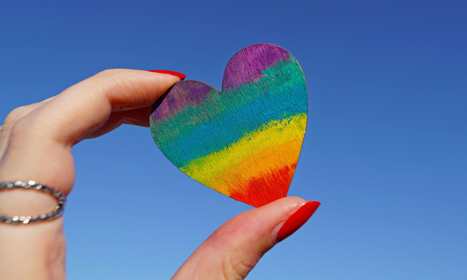 A woman is holding a rainbow heart in her hand.