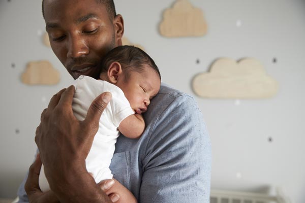 A man is holding a baby in his arms in a nursery. A man is holding a baby in his arms in a nursery.