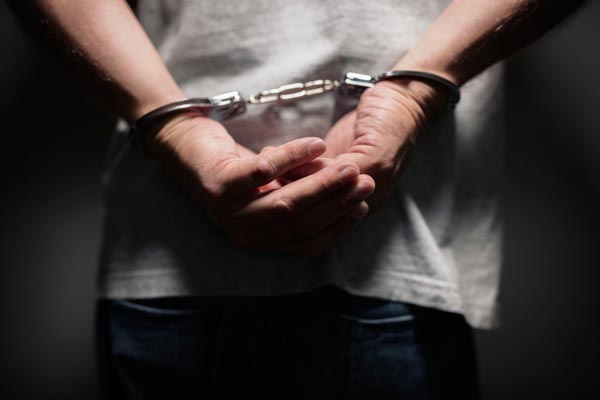 A man in handcuffs is standing in a dark room. A man in handcuffs is standing in a dark room.