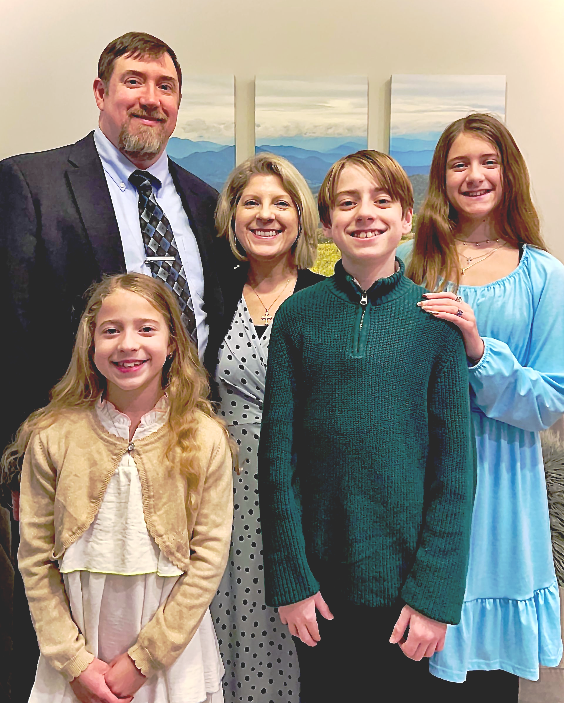 Victoria with her family is posing for a picture together in a park.