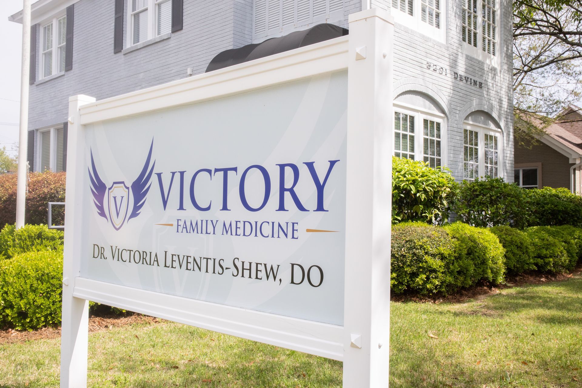 Sign for Victory Family Medicine outside a light gray building.