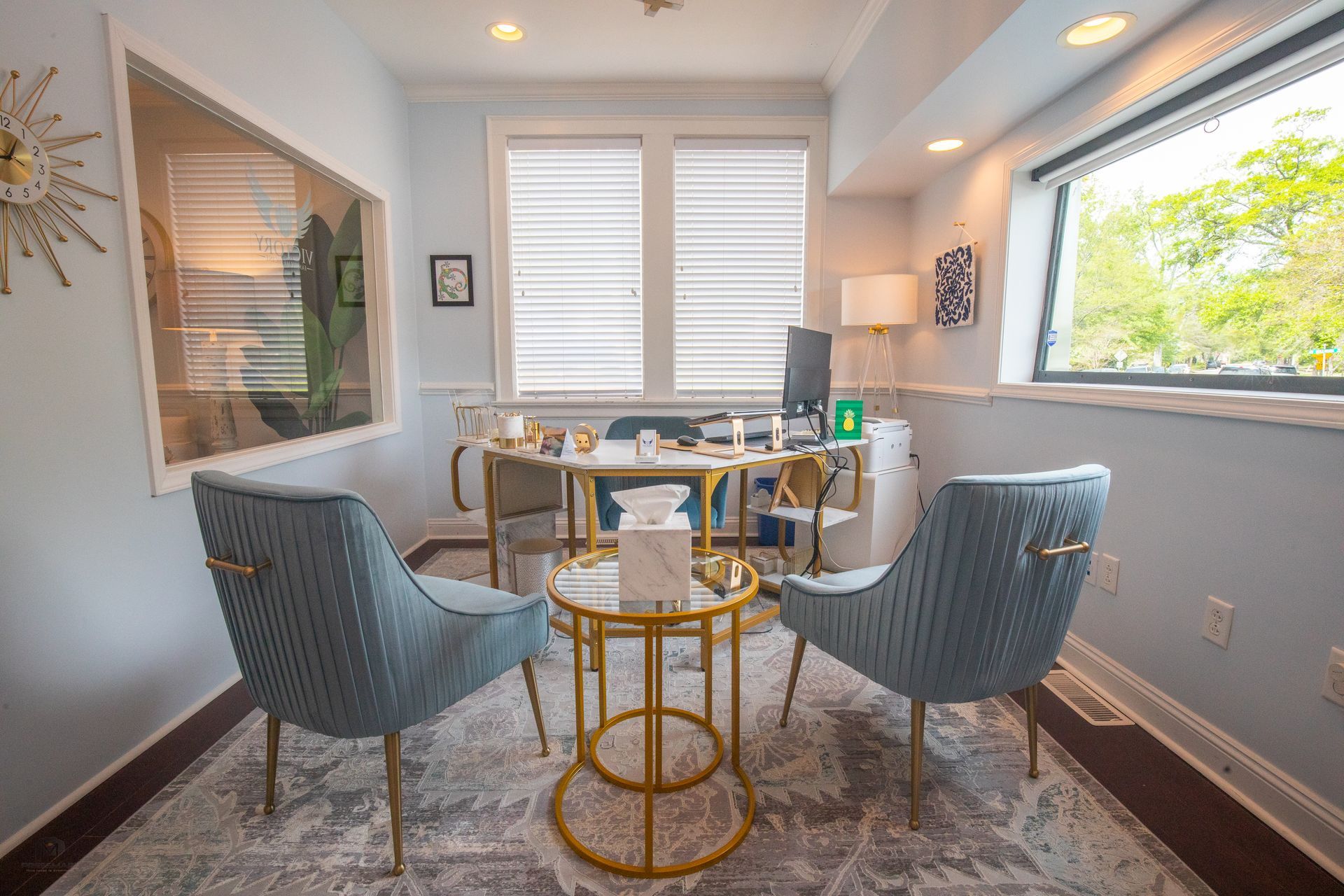 A calming office with blue chairs, a round table, and a window.