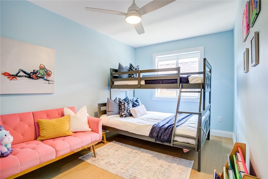 Bright kids’ bedroom with light blue walls, bunk beds, and a pink sofa.