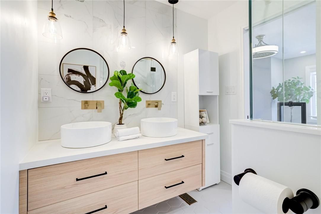 Bright primary bedroom with neutral tones, layered bedding, and a small desk by the window.