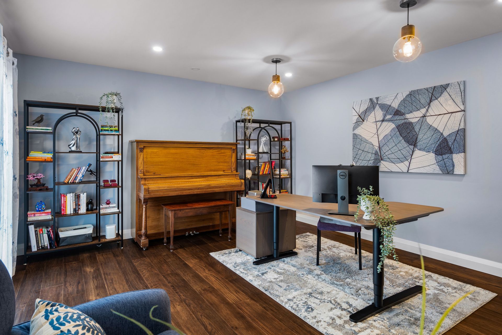 Modern home office with dual monitors, green accent chair, and dark blue walls.