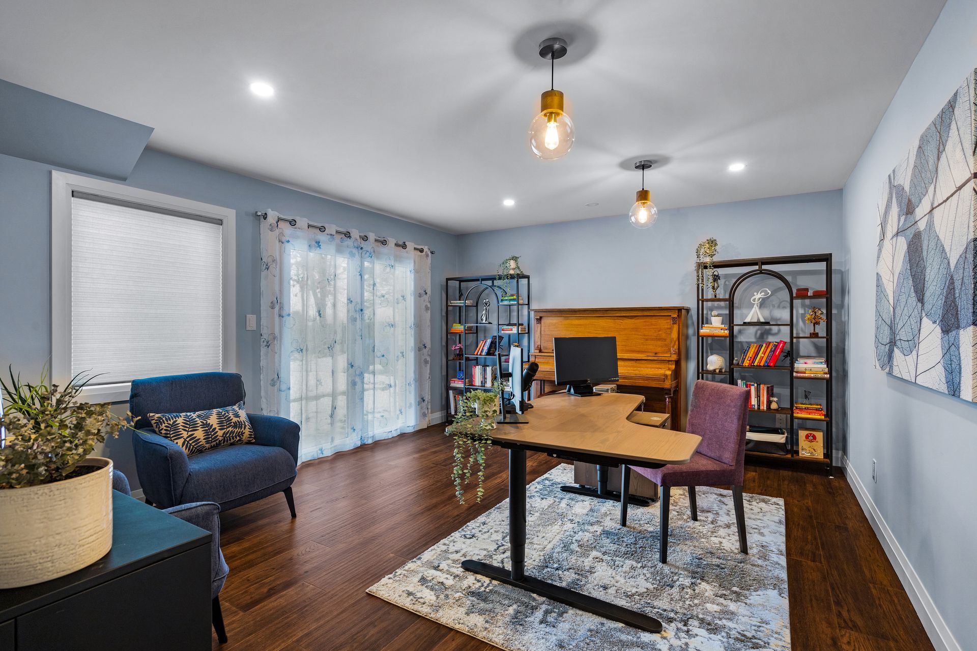 A modern home office with a wooden desk, bookshelves, cozy seating, and soft lighting.