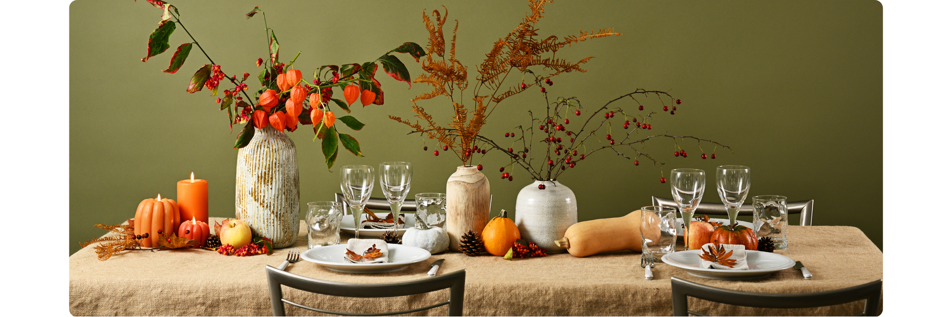 Elegant fall table setting with pumpkins, candles, and autumn floral centerpieces.
