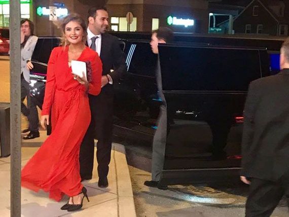 A woman in a red dress is walking next to a man in a suit.