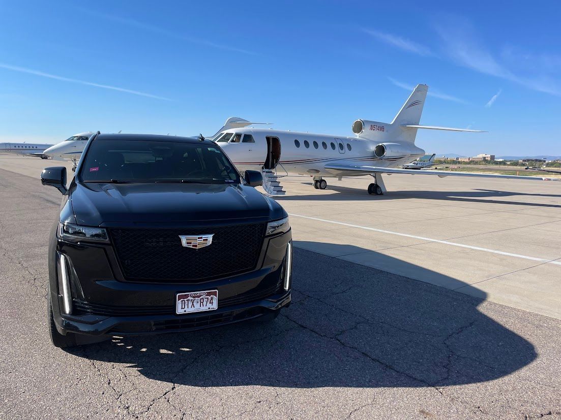 A black car is parked in front of a private jet on a runway.