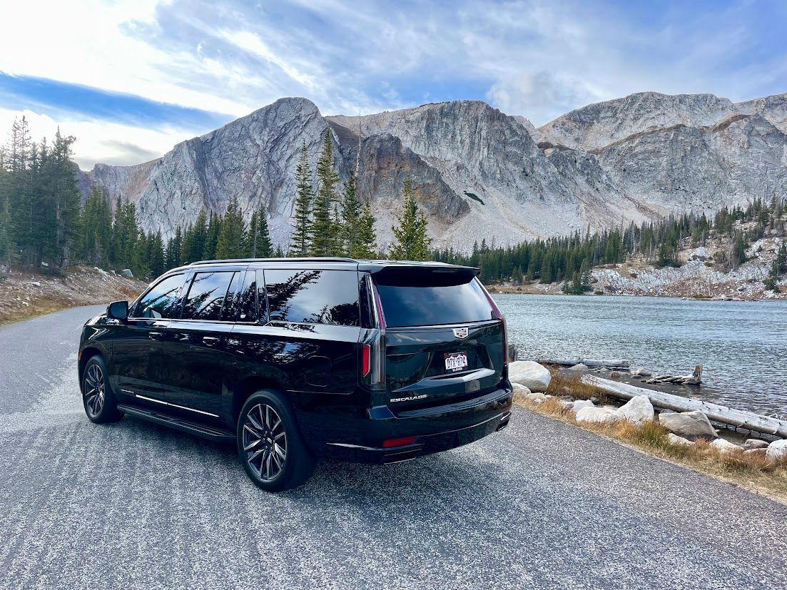 A black suv is parked on the side of a road next to a lake.