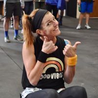 A woman is sitting on the floor giving a thumbs up.