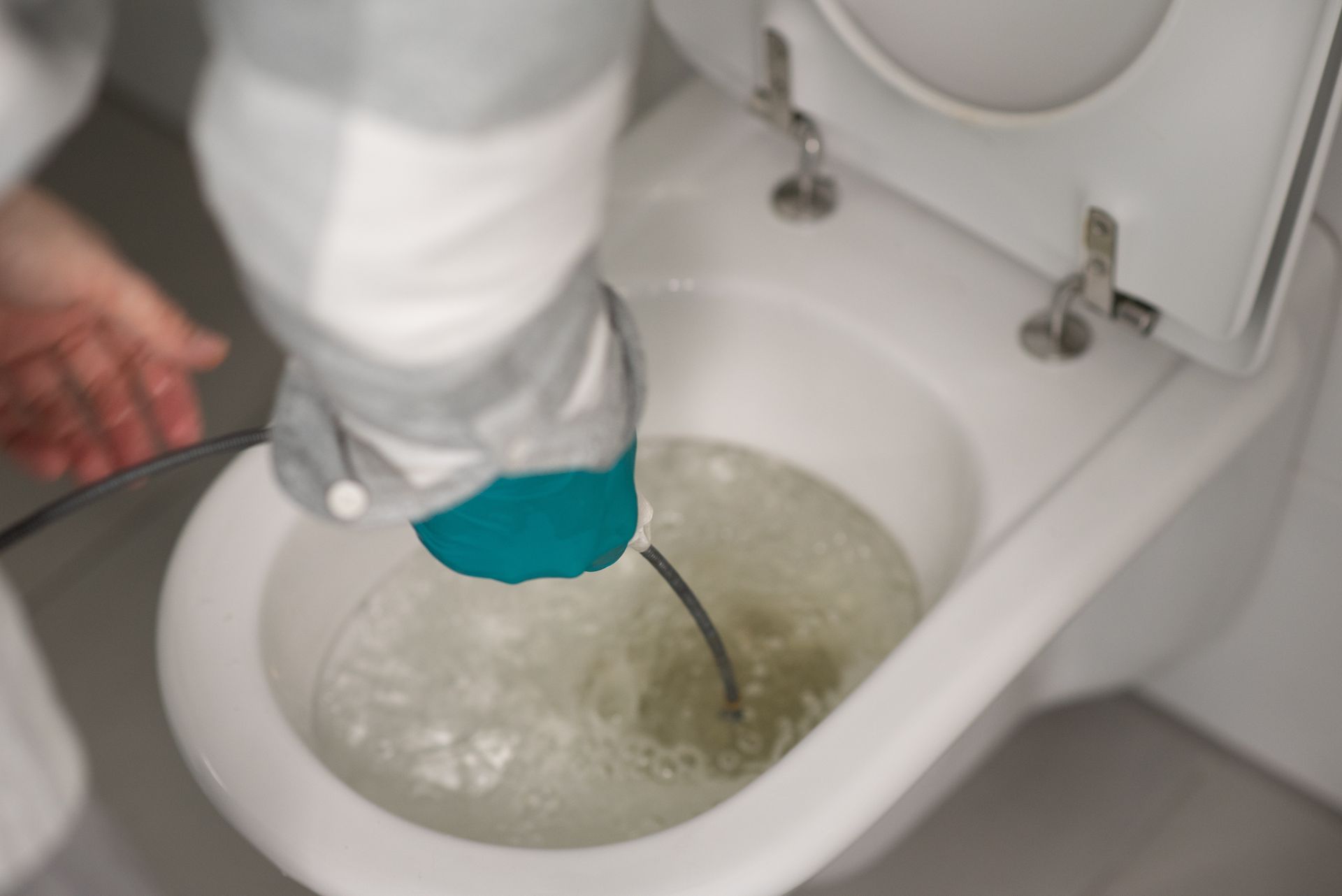 Plumber snaking a clogged toilet bowl to clear blockage during emergency drain service in NJ