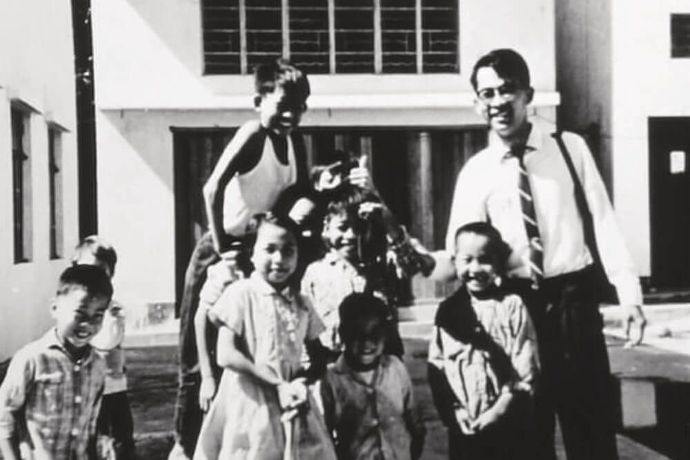 A black and white photo of a group of children and a man