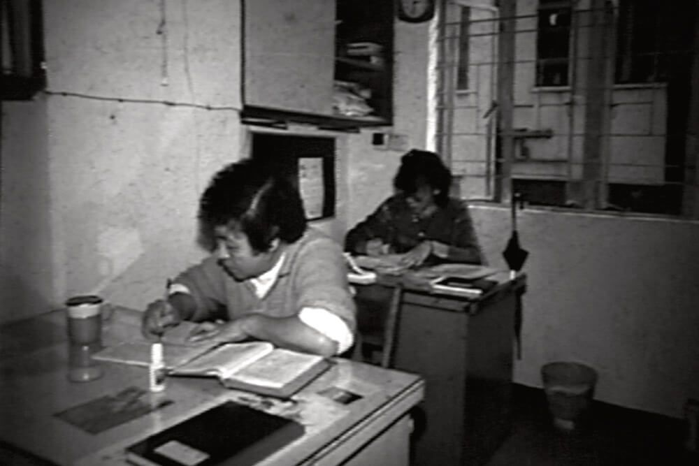 A black and white photo of two people sitting at desks