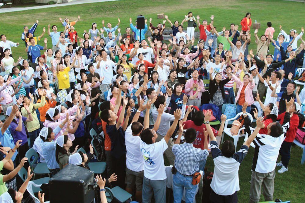 A large group of people are raising their arms in the air