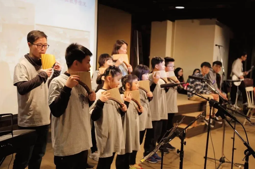 A group of children are singing into microphones on a stage.