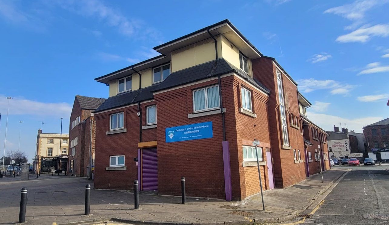 A large brick building with a purple door is sitting on the corner of a street.